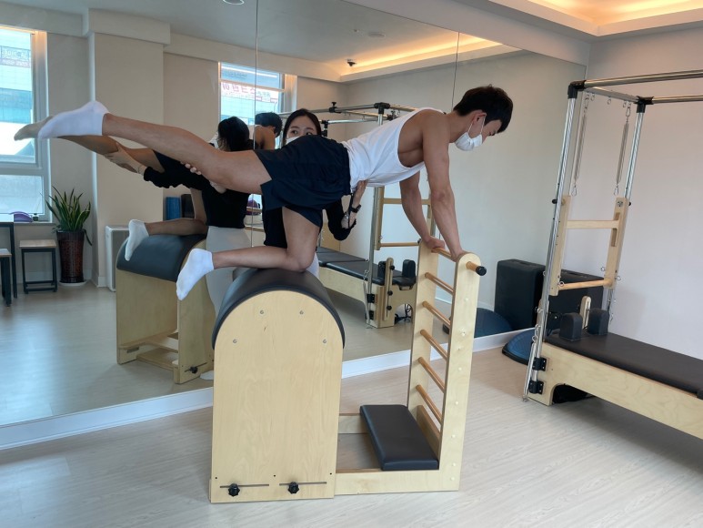 필라테스 리포머와 소형 덤벨이 함께 있는 스튜디오 전경